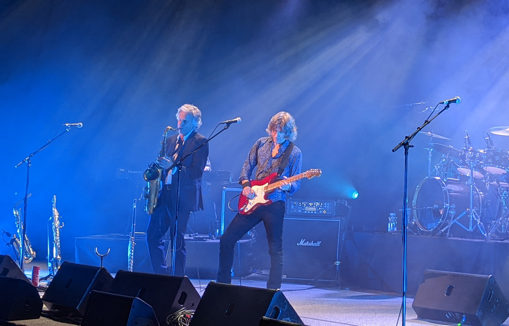 Nahaufnahme vom Saxofonisten und vom Sänger mit Gitarre nebeneinander beim Spielen