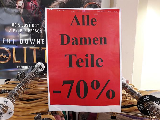 Werbetafel in Textil-Damenabteilung: "Alle Damen Teile -70 %"